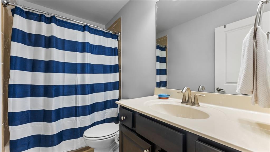 3418 Locust Cove Road Gainesville, GA 30504 - Photo 24 of 61 a bathroom with a sink a toilet a mirror and shower curtain