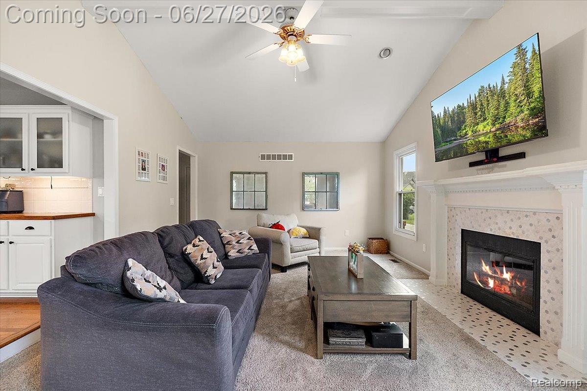 4193 Oak Tree Circle Rochester, MI 48306 - Photo 27 of 72 Family room featuring vaulted ceilings, exposed beam, ceiling fan, and a fireplace with a decorative tile surround and mantel