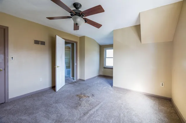 an empty room with a ceiling fan and a window
