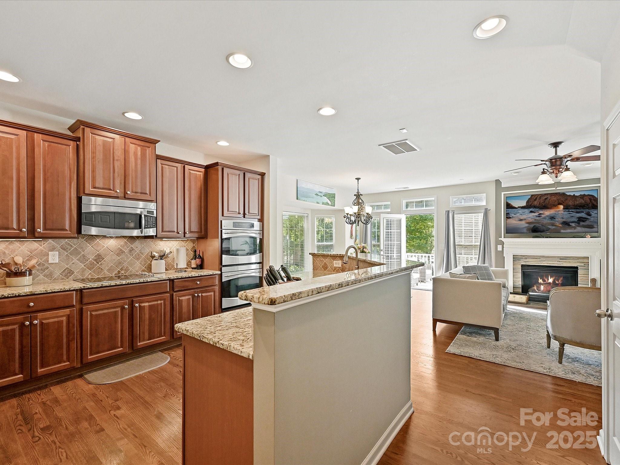 405 Armour Street Davidson, NC 28036 - Photo 5 of 33 a kitchen with stainless steel appliances granite countertop a stove top oven a sink dishwasher a dining table and chairs with wooden floor