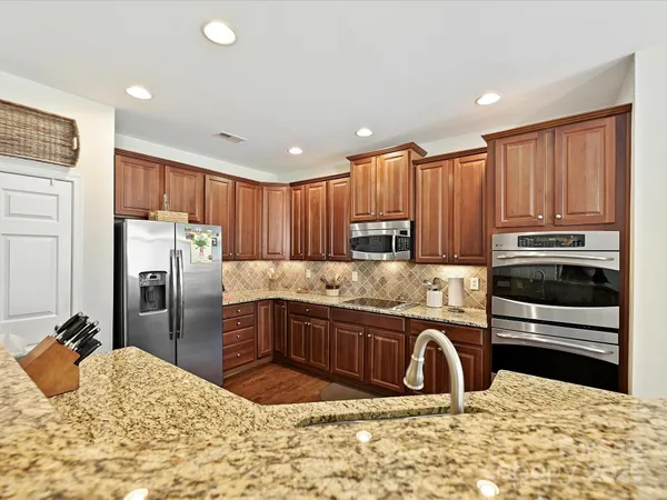 a kitchen with granite countertop a refrigerator and a stove top oven
