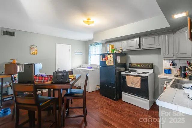 a kitchen with stainless steel appliances kitchen island granite countertop a table chairs and a refrigerator