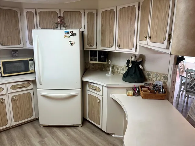a kitchen with a refrigerator and white cabinets