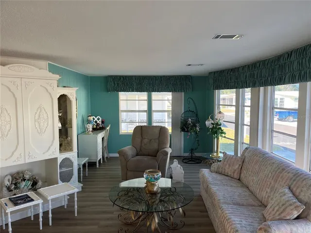 a living room with furniture a lamp wooden floor and a large window