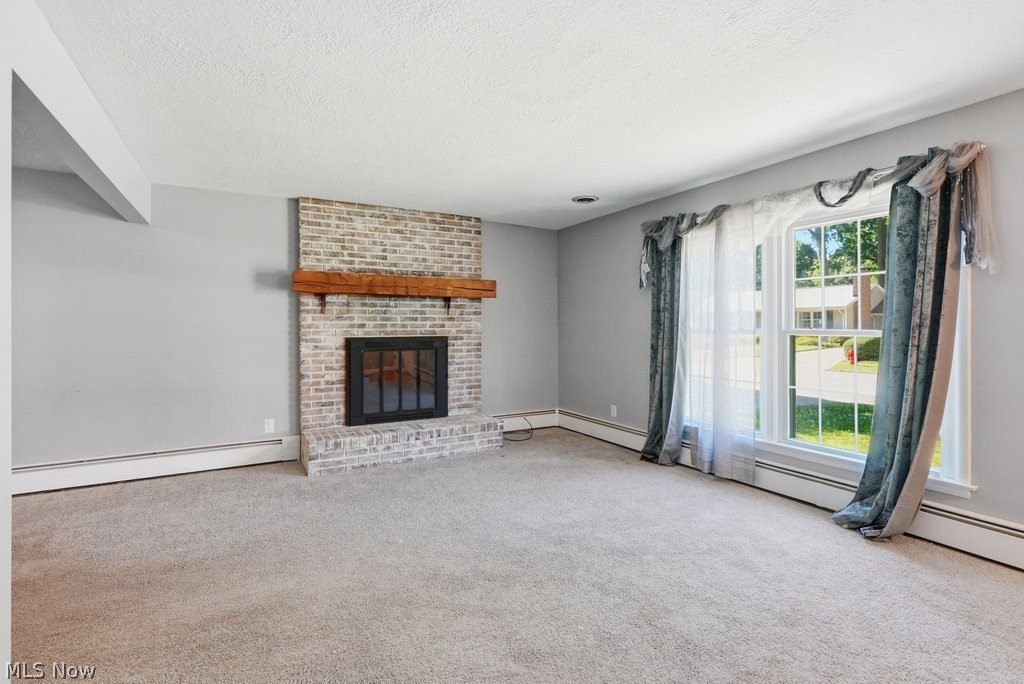 136 Pinehurst Road Munroe Falls, OH 44262 - Photo 6 of 48 Spacious living area featuring a brick-face fireplace with a wood mantel, light gray carpeting, and light gray wall paint