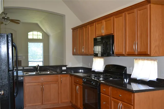 a kitchen with granite countertop stainless steel appliances a stove a refrigerator a sink and dishwasher with wooden cabinets