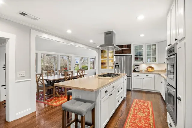 a large kitchen with cabinets chairs and wooden floor
