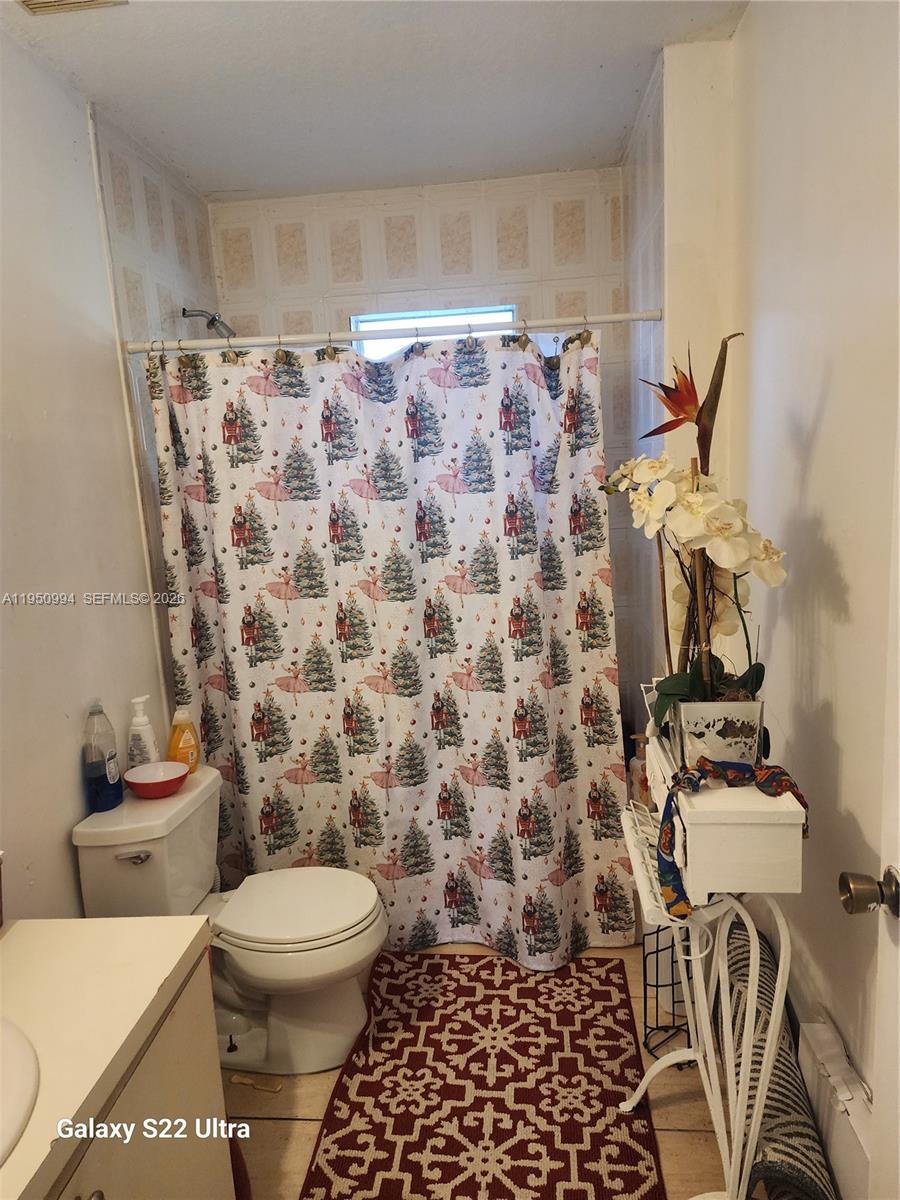1747 Northwest 85th Street Miami, FL 33147 - Photo 9 of 12 a bathroom with a toilet and a shower curtain