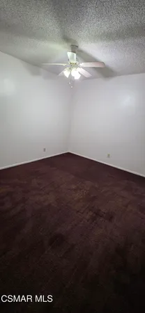 a view of a space with wooden floor a fan and a window