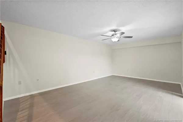 an empty room with wooden floor and a ceiling fan