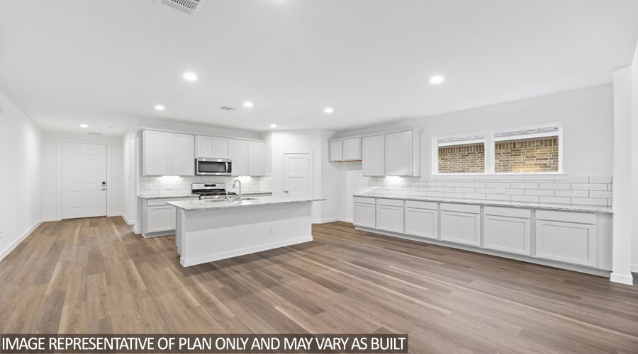 251 Springfield Terrace Drive Conroe, TX 77304 - Photo 5 of 23 a large white kitchen with kitchen island a sink a stove a refrigerator and white cabinets with wooden floor