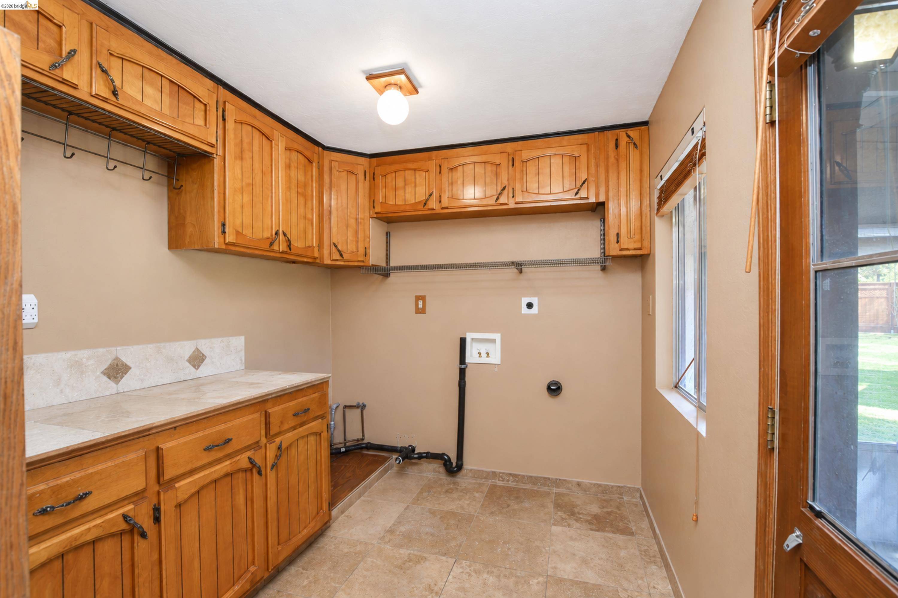 340 West Bolton Road Oakley, CA 94561 - Photo 21 of 87 Utility room featuring wood cabinetry, a tiled backsplash, and stone-finish flooring