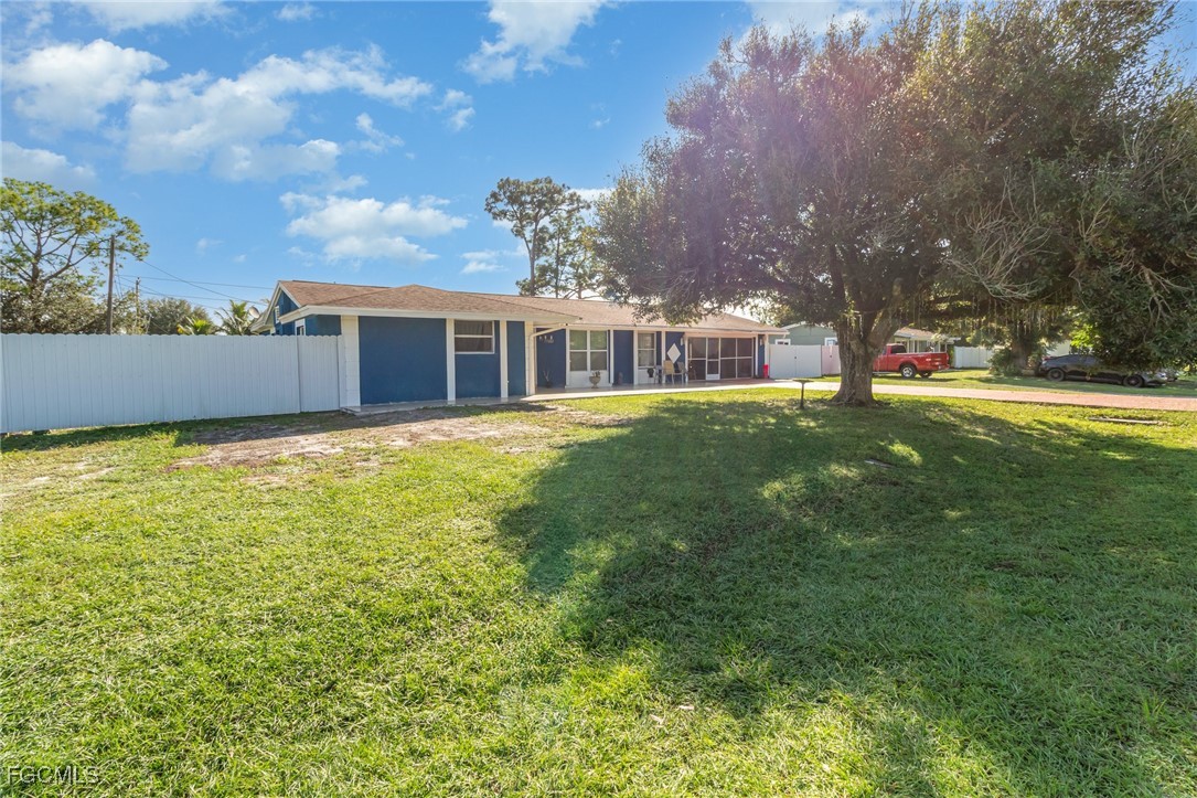18 Illinois Road Lehigh Acres, FL 33936 - Photo 2 of 28 a view of a house with a big yard and large trees