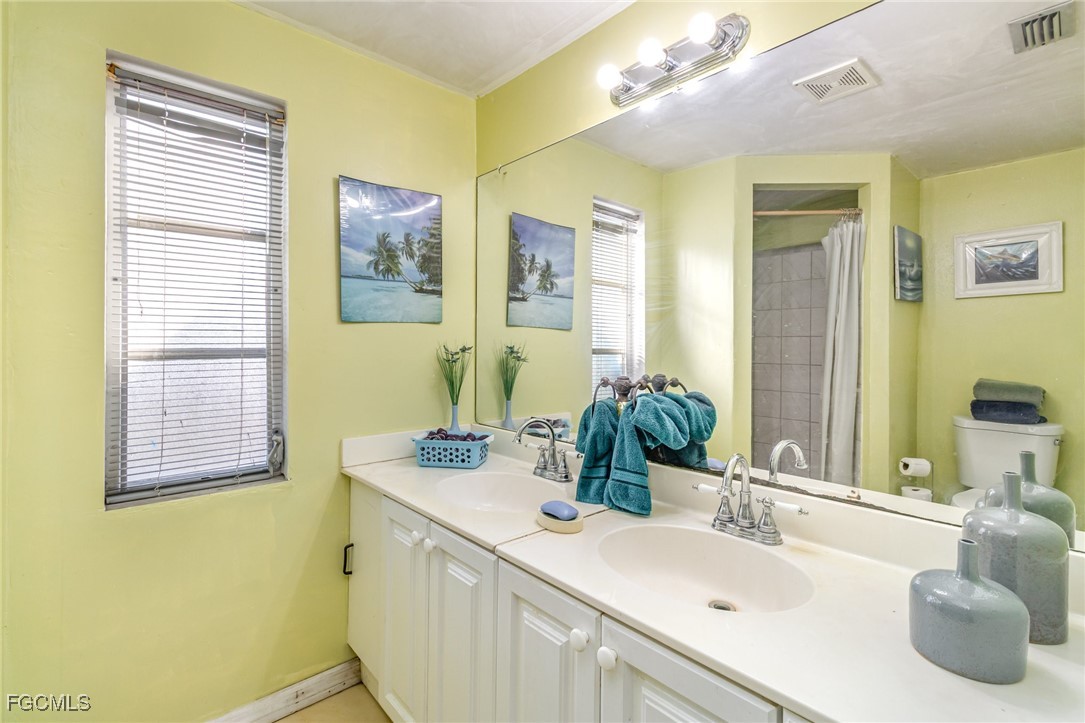 18 Illinois Road Lehigh Acres, FL 33936 - Photo 22 of 28 a bathroom with a double vanity sink a mirror and a