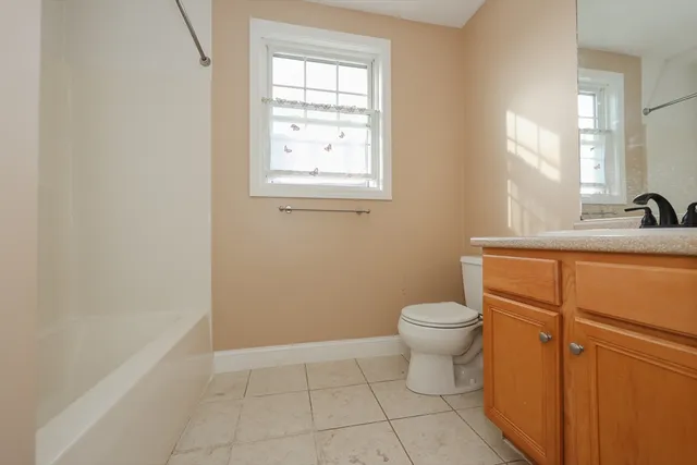 a bathroom with a granite countertop toilet a sink a mirror and a window