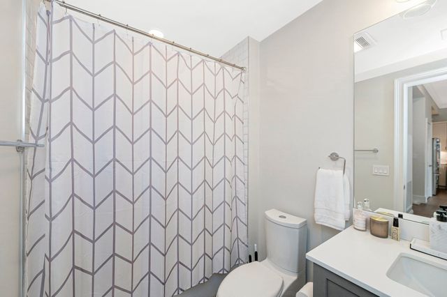 a white toilet sitting next to a white sink and curtain