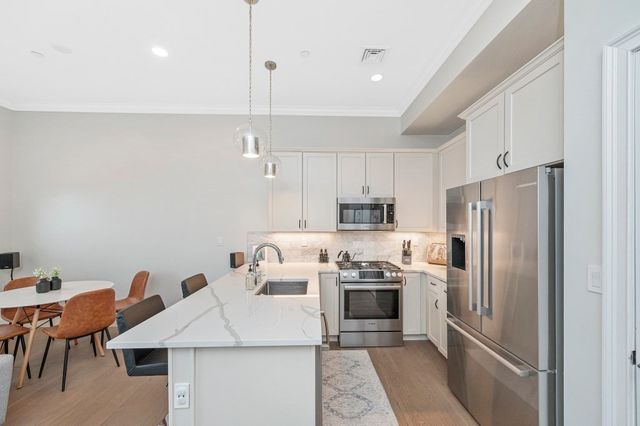 a kitchen with stainless steel appliances a refrigerator a sink a stove a table and chairs