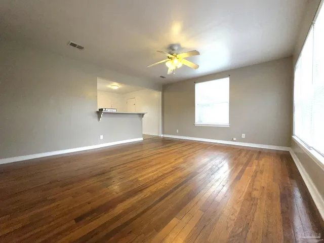 an empty room with wooden floor and windows