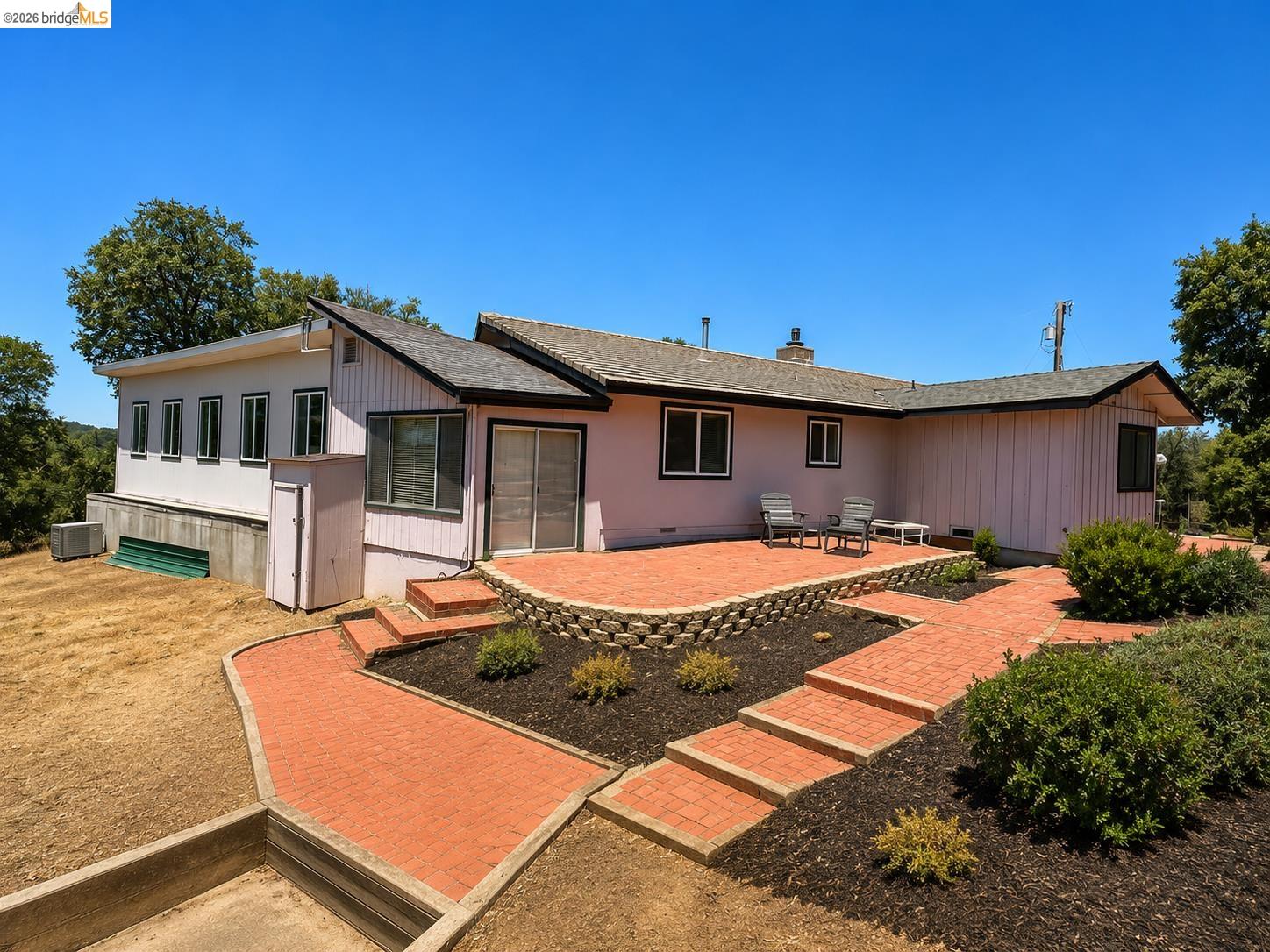 18195 Wards Ferry Road Sonora, CA 95370 - Photo 30 of 67 Rear exterior with a red brick patio and pathways, featuring a terraced landscape design