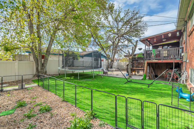 7470 Ramanee Drive Midvale, UT 84047 - Photo 28 of 29 Fenced backyard with a trampoline, a deck, a patio area, and a gate