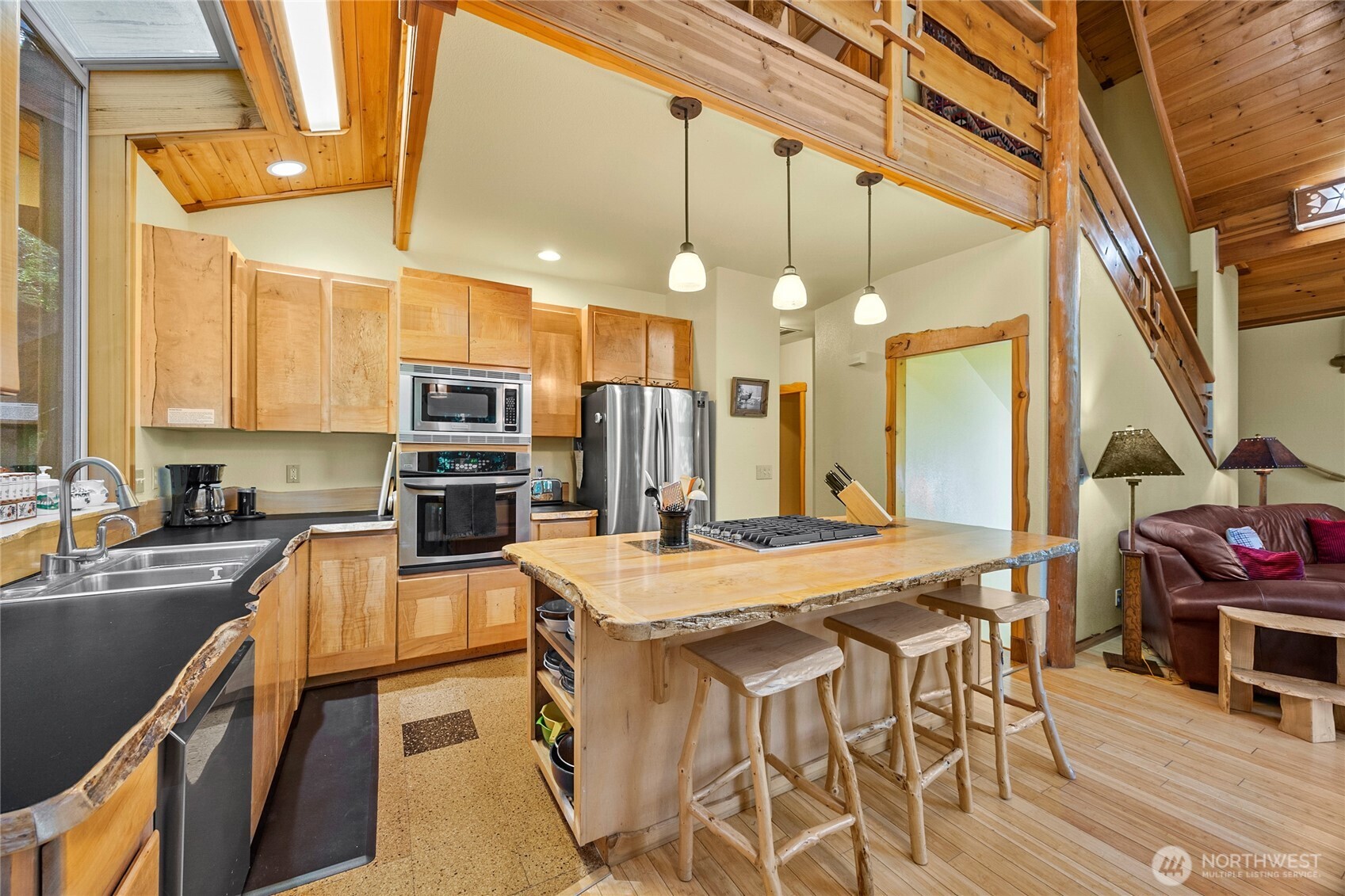 106 Timber Trail Packwood, WA 98361 - Photo 13 of 40 a kitchen with stainless steel appliances granite countertop a stove top oven a sink a dining table and chairs with wooden floor