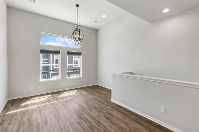 a view of an empty room with wooden floor and windows