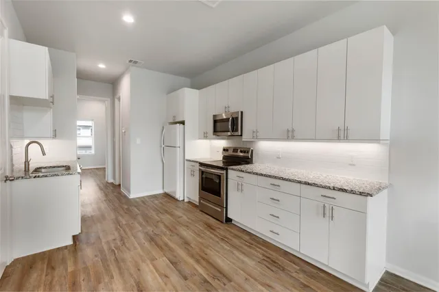 a kitchen with granite countertop white cabinets and stainless steel appliances