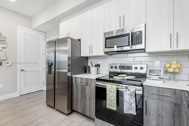 a kitchen with stainless steel appliances a stove a microwave a sink and cabinets