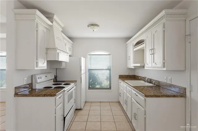 a kitchen with granite countertop a sink stove and cabinets