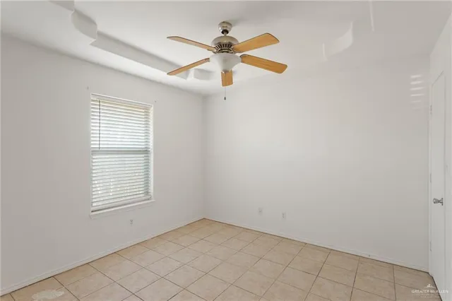 an empty room with ceiling fan and window