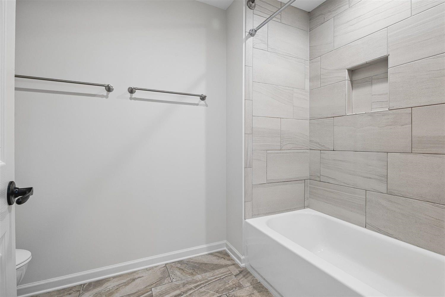 8970 Farmoor Road Germantown, TN 38139 - Photo 27 of 35 White soaking tub with light gray tile surround, integrated shower niche, and ceiling-mounted shower head