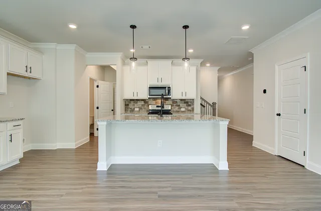 a kitchen with stainless steel appliances granite countertop a refrigerator a stove a sink and white cabinets with wooden floor