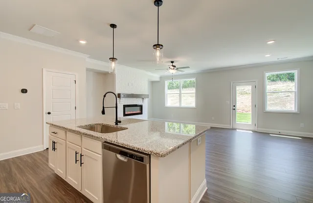 a kitchen with stainless steel appliances granite countertop a sink stove and white cabinets with wooden floor