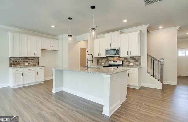a view of kitchen with stainless steel appliances granite countertop cabinets and wooden floor