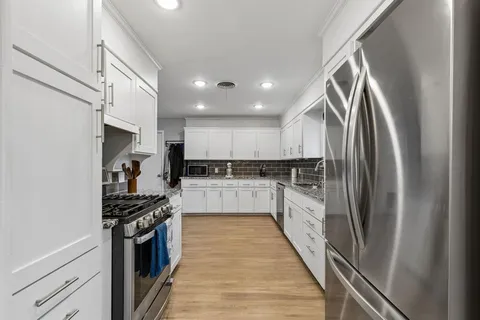 a kitchen with stainless steel appliances a refrigerator sink and white cabinets