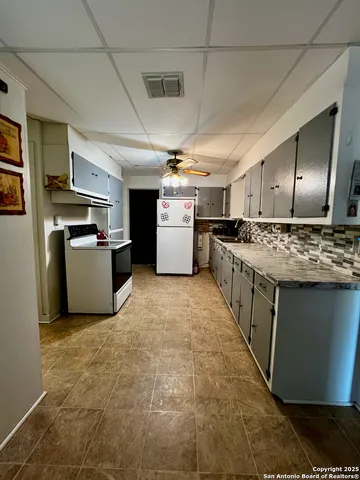 a kitchen with a stove a refrigerator and furniture