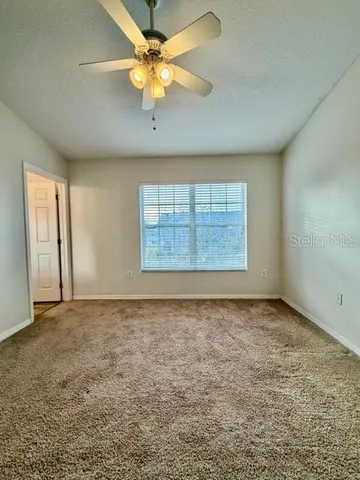 an empty room with windows and fan