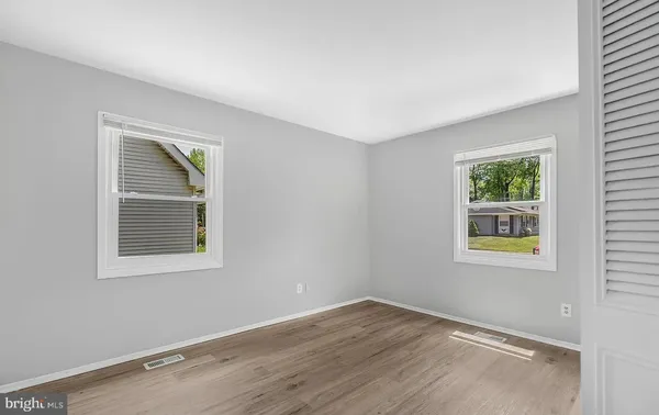 an empty room with wooden floor closet and windows