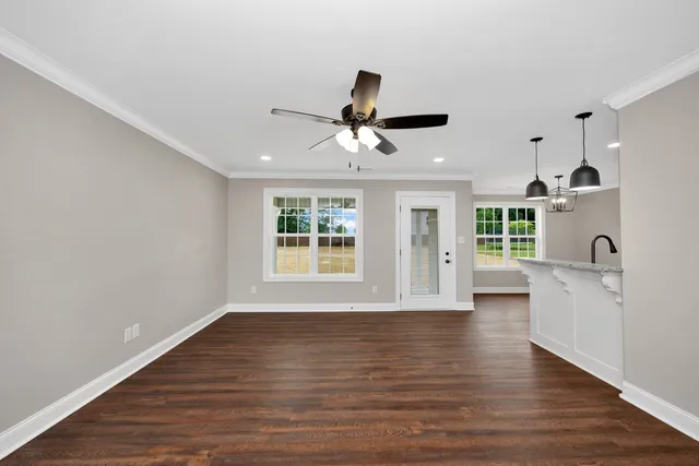 a view of an empty room with a window and wooden floor