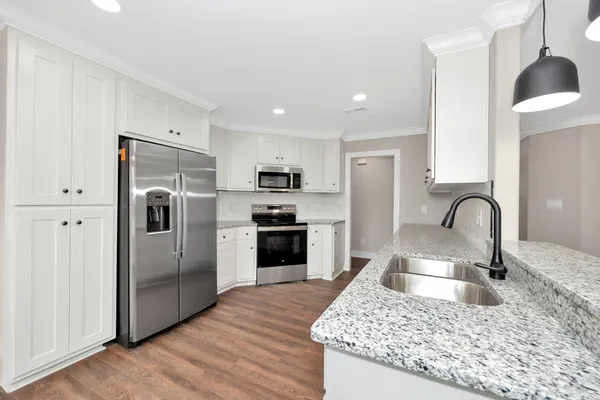 a kitchen with stainless steel appliances granite countertop a refrigerator a sink a stove and oven