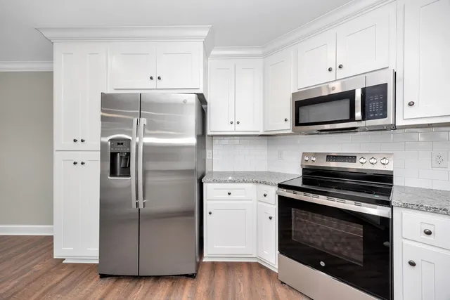 a kitchen with cabinets stainless steel appliances and wooden floor