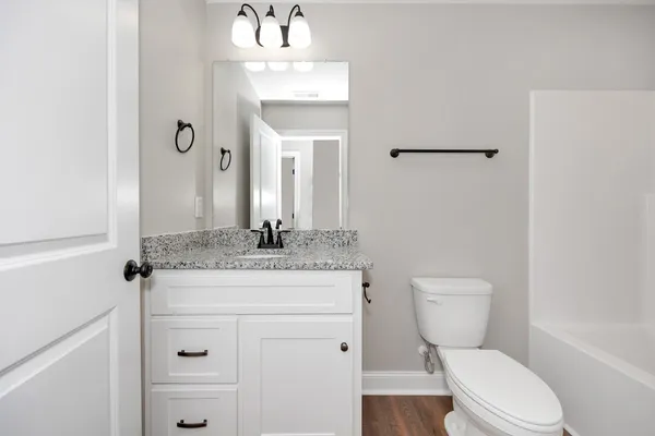 a bathroom with a granite countertop toilet sink and mirror