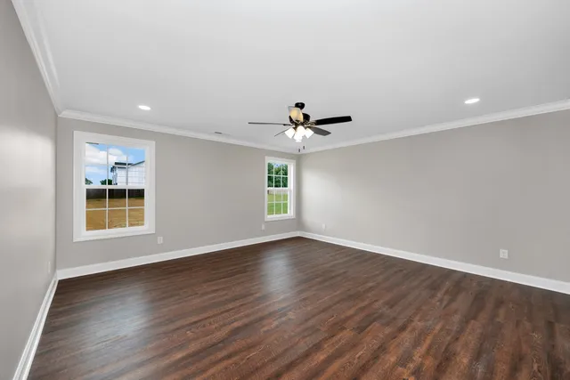a view of an empty room with a window and wooden floor