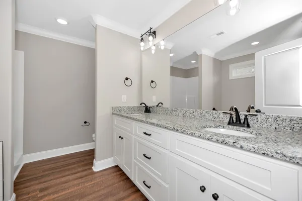 a bathroom with a granite countertop double vanity sink a mirror and a