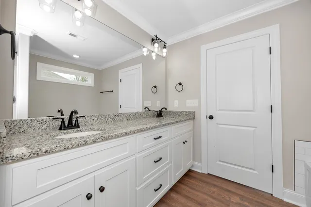 a bathroom with a granite countertop double vanity sink a mirror and vanity