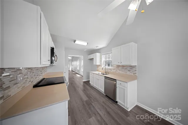 a large kitchen with a stove and white cabinets