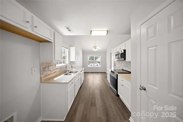 a kitchen with granite countertop a sink stove refrigerator and cabinets