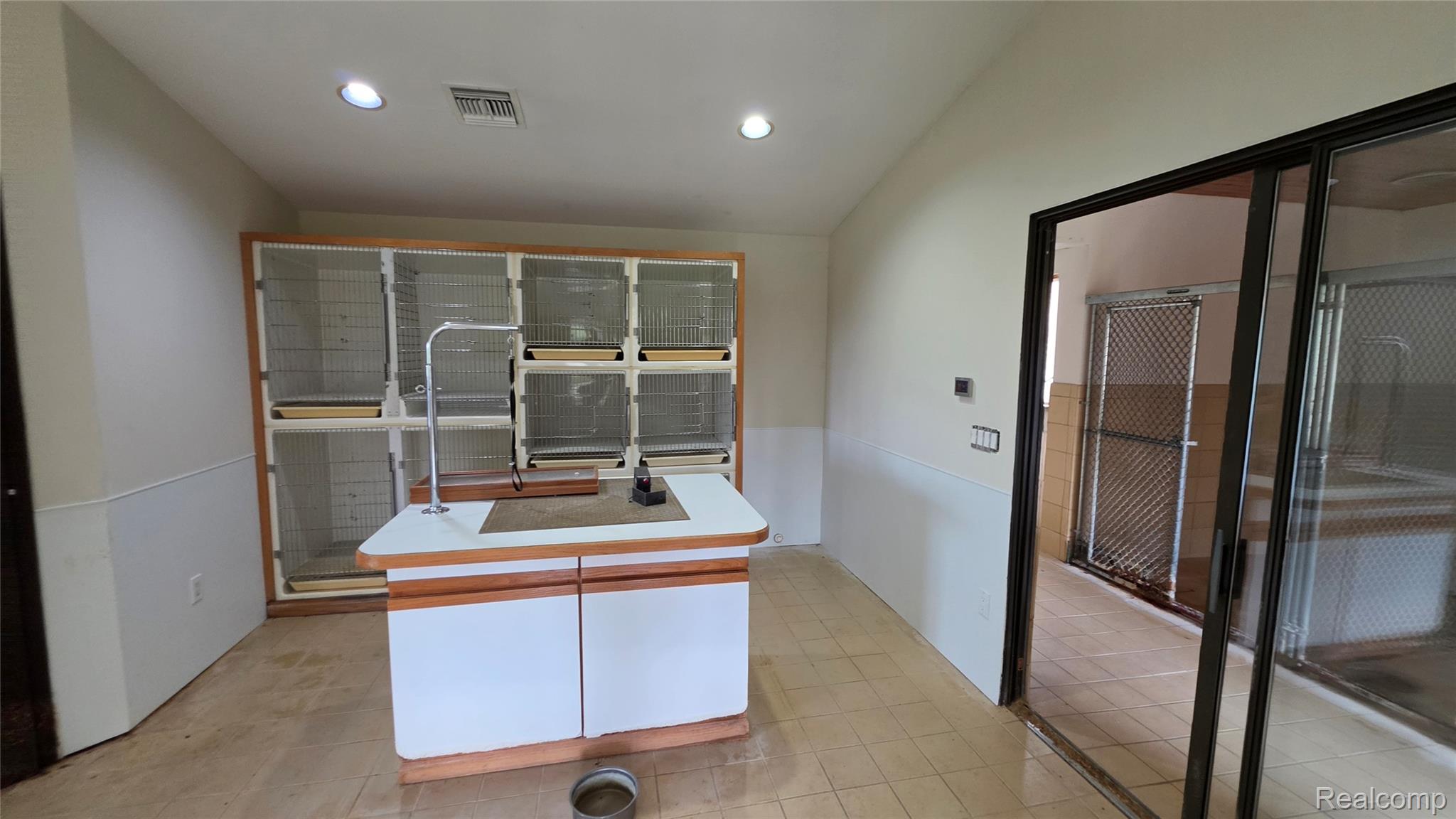 2551 Patterson Lk Road Pinckney, MI 48169 - Photo 27 of 37 Kennel. Tile flooring with built-in cabinetry featuring multiple compartments, a central island with an attached faucet, and sliding glass doors