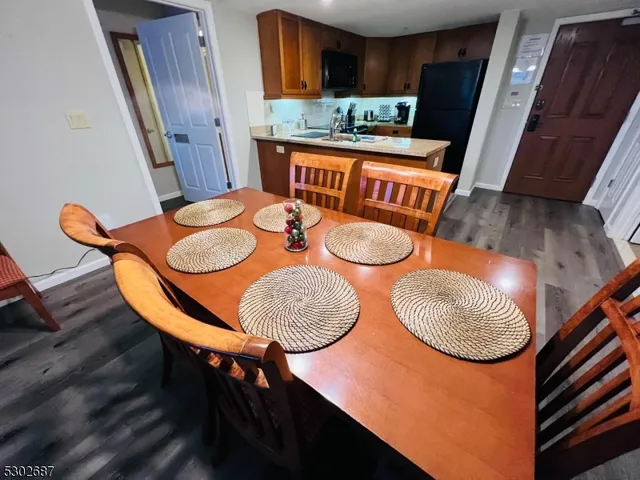 a room with stainless steel appliances kitchen island granite countertop wooden floor a dining table and chairs