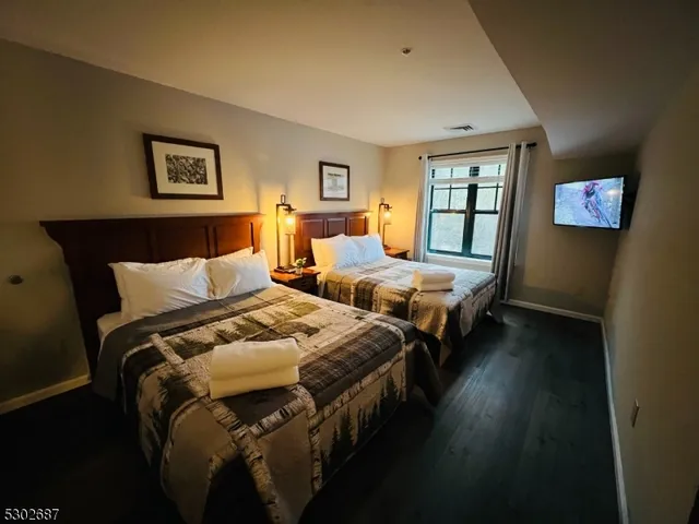 a bedroom with two beds and wooden floor